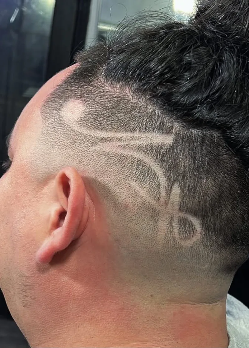 Skin fade with a scissor hair design, top knot kept long